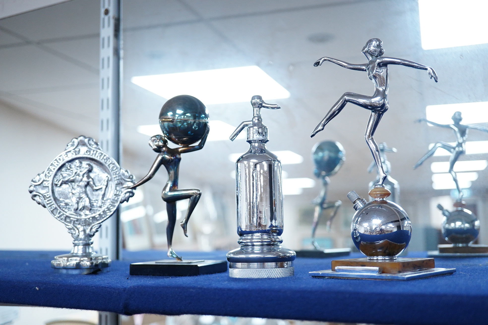 Five chrome and brass car mascots, including a knight, a policeman, a figure of Mercury, etc. together with two Art Deco table lighters as female figures, and an ashtray with the figure of a blacksmith (8)